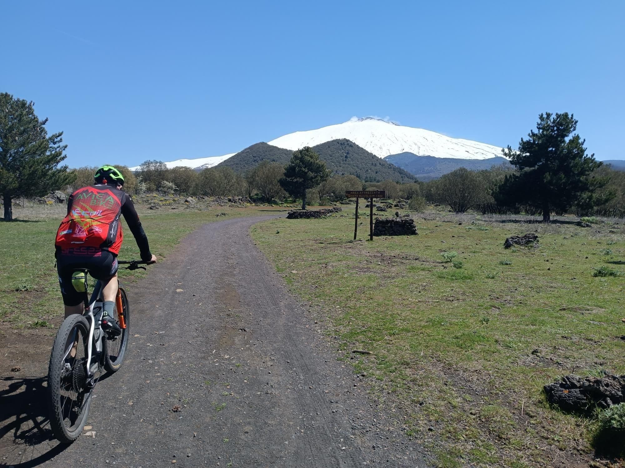 Un ciclista sulla pista verso l'area attrezzata di Monte Ruvolo, con la cima dell'Etna innevata sullo sfondo
