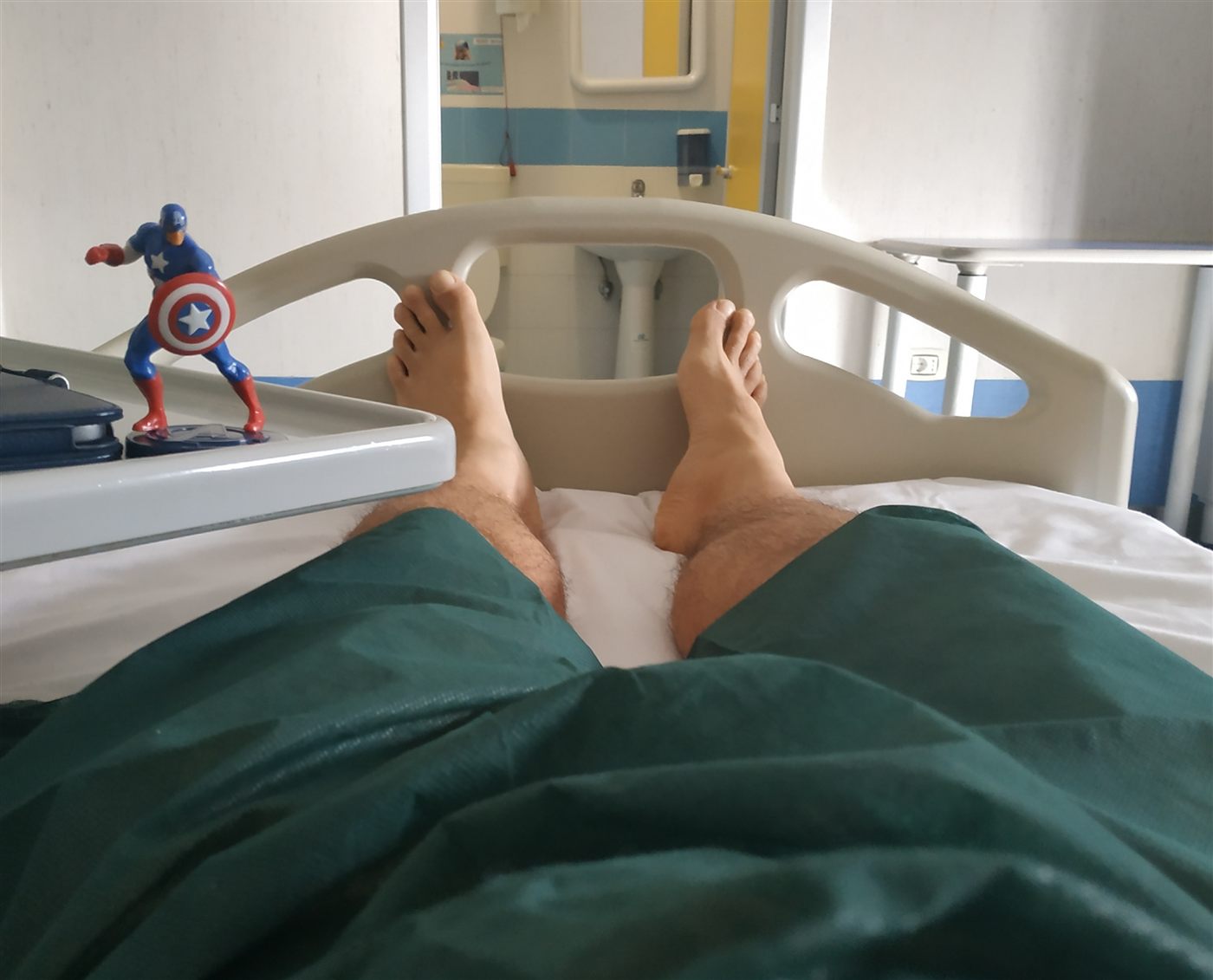 Disteso nel letto d'ospedale, con una statuina di Capitan America sul tavolino