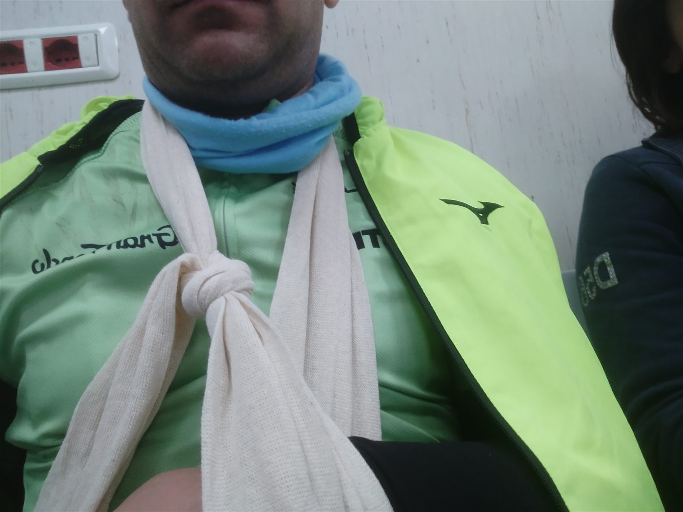 In sala d'aspetto con il braccio al collo, ancora in tenuta da ciclista